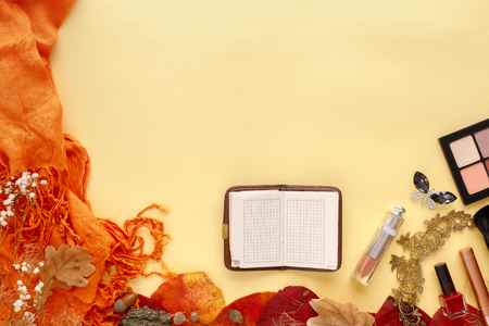autumn leaves, scarf, paper notebook and laptop on yellow backgroundの写真素材