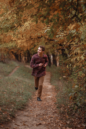 Handsome young guy in nature on an autumn dayの写真素材