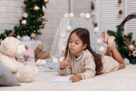 Cute child girl writing letter to Santa Claus at homeの写真素材