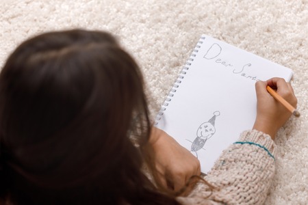 Cute child girl writing letter to Santa Claus at homeの写真素材