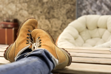 male feet with orange shoes relaxing on wooden tableの写真素材