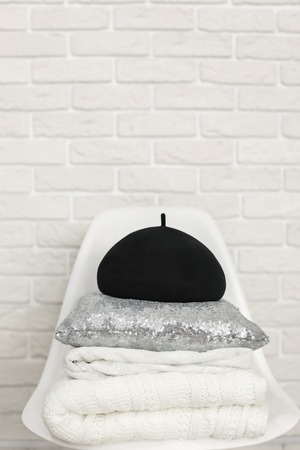 black hat, pillow and knitted blanket on chairの写真素材
