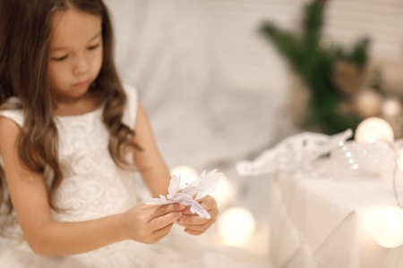 child girl makes paper snowflakes for decoration Christmas treeの写真素材