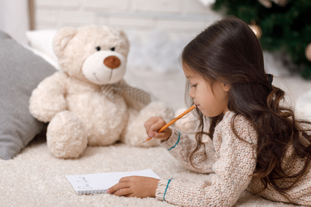Cute child girl writing letter to Santa Claus at homeの写真素材