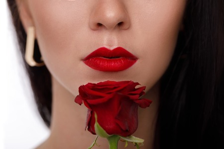 female lips with bright red makeup and red rose flower.の写真素材