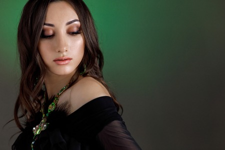 beautiful woman with beautiful hair, makeup and with luxury necklace on dark green background.の写真素材