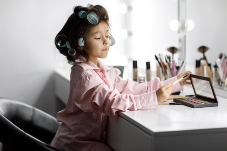Cute little girl playing with her mothers cosmeticの写真素材