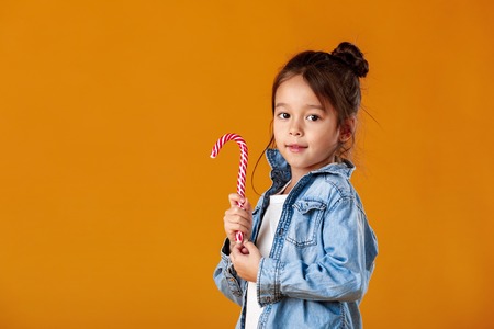 happy little girl in jeans clothes holding lollipop