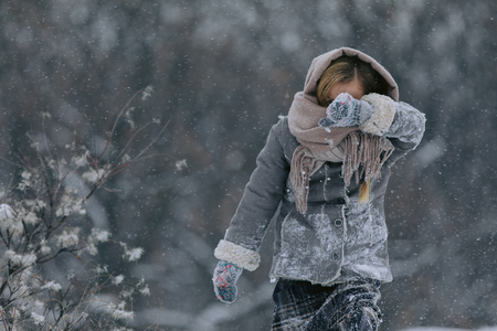 cute little child girl in the forest in winter. snowing and snowstormの写真素材