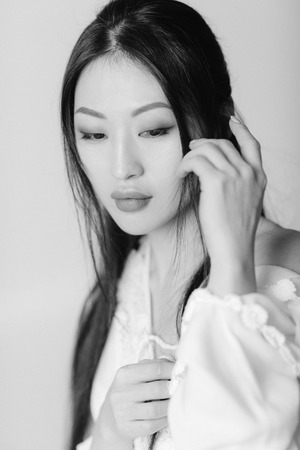 portrait of beautiful asian woman in white shirt posing in studio. black and white shotの写真素材