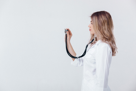 Medical physician doctor woman in white coat examining with stethoscope on light background.の写真素材
