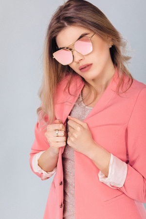 Fashion portrait of attractive elegant blonde woman in pastel pink jacket and sunglasses posing in studio. woman dressed in trendy spring outfitの写真素材