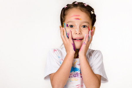 cute surprised little child girl with hands painted in colorful paint isolated on white background.の写真素材
