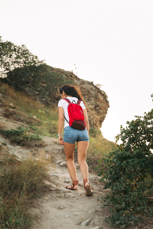 tourist girl with a backpack rises up the pathの写真素材