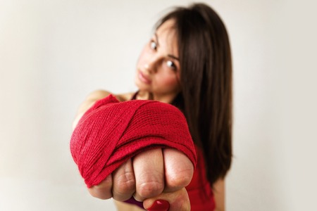 beautiful woman boxer with red strap on wrist. Fitness girl preparing for boxing training. focus on fistの写真素材