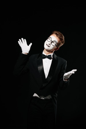 portrait of smiling mime man in tuxedo and glasses on black background