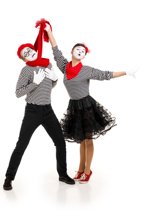 Smiling mimes in striped shirts. Man and woman dressed as actors of pantomime theater isolated on white backgroundの写真素材