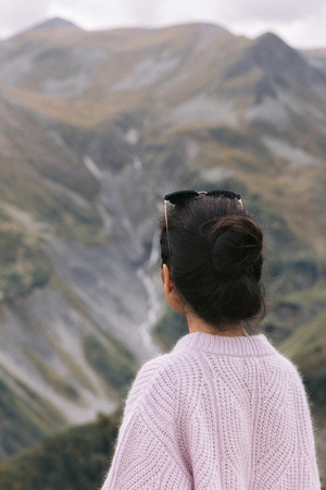 young girl in a sweater is looking at the Caucasian mountains, Georgia, rear view.の写真素材