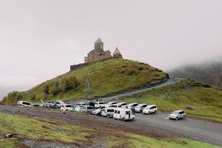 Trinity Church of Gergety, Georgia - September 17, 2018: tourists near the Trinity Church of Gerget on a rainy autumn day, Georgiaのeditorial素材