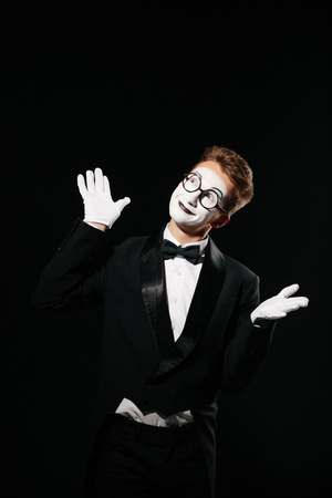 portrait of smiling mime man in tuxedo and glasses on black backgroundの写真素材