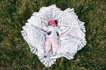 little girl baby lies on the green lawn. top view