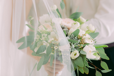 brides hands hold beautiful bridal bouquet of white roses.の写真素材