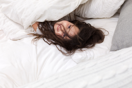 adorable little child girl smiling after waking up in bedの写真素材