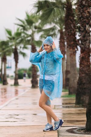young woman tourist in raincoat smiling and looking at the camera under rainの写真素材