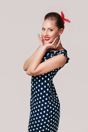 portrait of smiling pin up woman in polka dot dress. cute girl in retro styleの写真素材