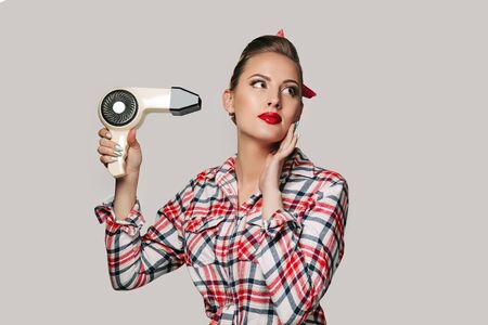Happy young brunette woman with hair dryer. pin-up retro styleの写真素材