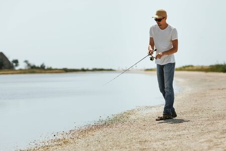 Young man fishing at sea from the shore. fisherman uses spinningの写真素材