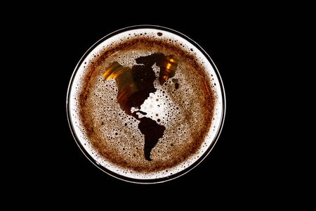 map of america shape on foam in glass of beer on black background Top view