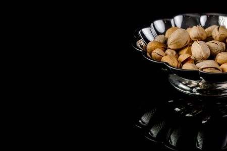 plate of salted pistachio nuts on black background.の写真素材
