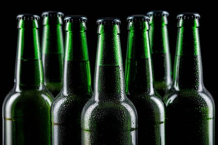 Row of wet glass bottles of beer on dark backgroundの写真素材