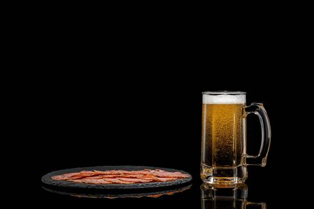 glass of beer and delicious sliced sausages on stone boardon black background. copy spaceの写真素材