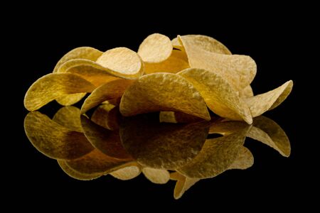 Salty delicious potato chips isolated on black backgroundの写真素材