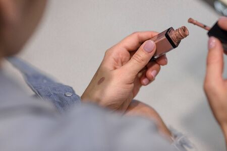 woman customer is testing lipstick by putting it on her arm in make-up shop.の写真素材