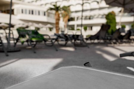 sunbed in the foreground and blur deck chair, sun umbrella and palm in hotel on backgroundの写真素材