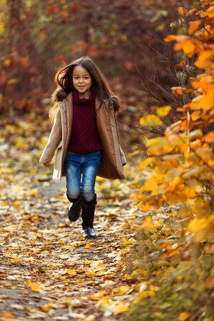 Happy adorable little girl runs in the autumn park. happy childhoodの写真素材