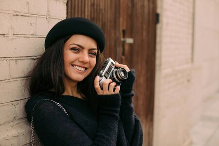 happy smiling woman in hat holding retro camera and taking pictureの写真素材