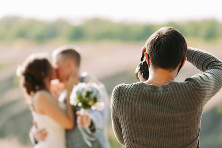 wedding photographer takes pictures of the bride and groom in nature in autumn, the photographer in actionの写真素材