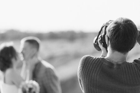wedding photographer takes pictures of the bride and groom in nature in autumn, the photographer in actionの写真素材