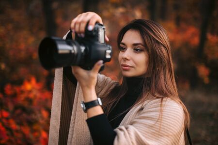 beautiful woman photographer takes pictures in nature in autumn, the photographer in action
