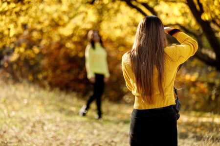 young woman photographer takes pictures of model in nature, the photographer in actionの写真素材