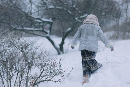 cute little child girl in the woods in winter. snowing and snowstorm