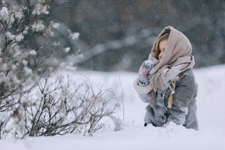 cute little child girl in the forest in winter. snowing and snowstormの写真素材