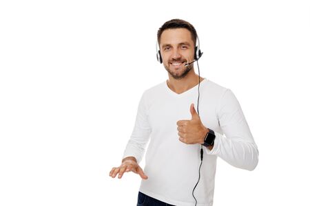 Call center worker man isolated on white background. Young smiling employee telesales agent using headset and showing Ok signの写真素材