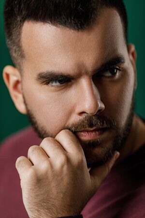 bearded man thinking about something on green background.