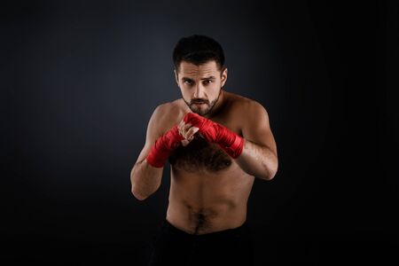 boxer man with red bandage on hands training before fight and showing the different movements on black backgroundの写真素材