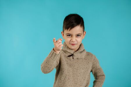 Cute little boy pointing camera on blue background. child pointing at you.